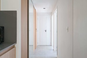 A hallway with a microwave, wooden panel, white doors, and a light switch. - MOT Rentals + Black Ravignani 2C - 2 Bd Palermo Hollywood (Buenos Aires)