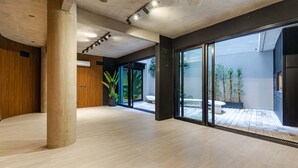 Een ruim interieur met een betonnen plafond, grote ramen en uitzicht op een patio.