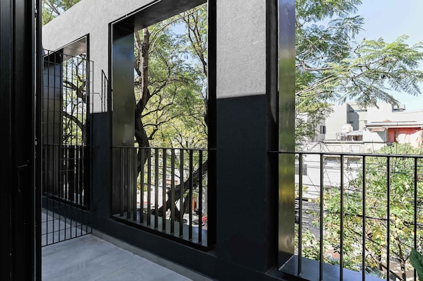 A balcony with a metal railing, a view of trees, and a building in the background. - MOT Rentals + Black Ravignani 2A - 3 pax Loft Palermo Hollywood (Buenos Aires)