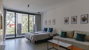 Ein modernes Schlafzimmer mit einem großen Bett, einer Couch, einem Couchtisch und einer Glastür, die auf einen Balkon führt.