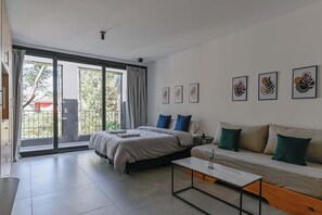 A modern bedroom with a large bed, a sofa, a coffee table, and a sliding glass door leading to a balcony. - MOT Rentals + Black Ravignani 2A - 3 pax Loft Palermo Hollywood (Buenos Aires)