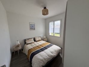 Ein Schlafzimmer mit einem Bett, Nachttischen, einem Fenster und einer Pendelleuchte.