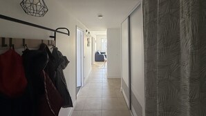 Eteinen, jossa on naulakko, riippuvalaisin ja kuviollinen verho.