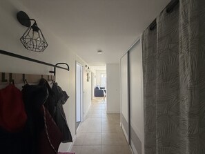 Ein Flur mit Kleiderhaken, einer Hängeleuchte und einem gemusterten Vorhang.