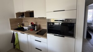 Moderni keittiö, jossa on valkoiset kaapit, sisäänrakennettu uuni ja mikroaaltouuni.