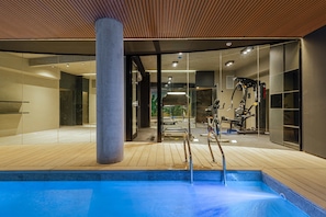 A modern indoor pool area with a wooden deck, exercise equipment, and glass walls. - MOT Rentals Design SohoHaus - 3 Lux Lofts 'A' 9 pax (Buenos Aires)