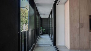 A narrow corridor with a black railing, a potted plant, and a wooden cabinet. - MOT Rentals Black Ravignani - 3 Lux Aparts 12 pax in Palermo Hollywood (Buenos Aires)