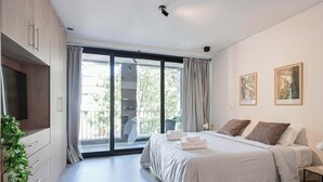 A modern bedroom with a large bed, a flat-screen TV, and a sliding glass door leading to a balcony. - MOT Rentals Black Ravignani - 3 Lux Aparts 12 pax in Palermo Hollywood (Buenos Aires)