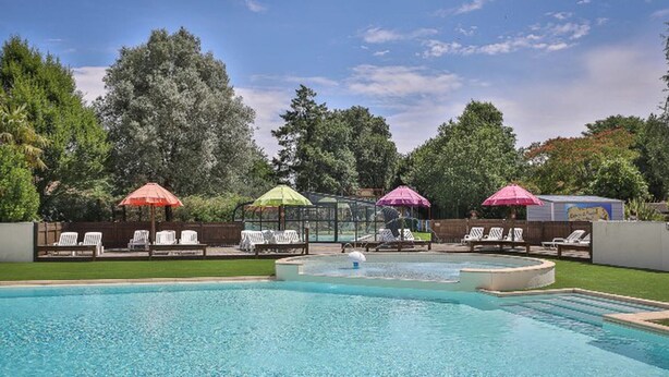 A swimming pool with lounge chairs and umbrellas, surrounded by trees and a clear sky. - Comfortable mobile home - 2 guests (Les Achards)