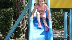 A child on a blue slide at a playground. - Comfortable mobile home - 2 guests (Les Achards)