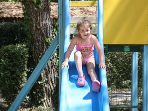 A child on a blue slide at a playground. - Comfortable mobile home - 2 guests (Les Achards)