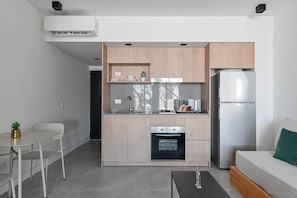 A modern kitchen with a built-in oven, a refrigerator, and a dining area with a table and chairs. - MOT Rentals + Black Ravignani 2B - 3 pax Loft Palermo Hollywood (Buenos Aires)