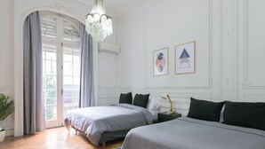 Hotellihuone, jossa on kaksi sänkyä, kattokruunu, ruukkukasvi ja näkymä ikkunasta.