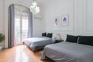 Ein Hotelzimmer mit zwei Betten, einem Kronleuchter, einer Topfpflanze und Blick durch ein Fenster.
