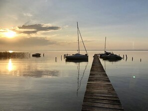A calm waterfront with a wooden dock leading to three sailboats anchored at the end. - Villa lake view with pool - 12 guests (Biscarrosse)