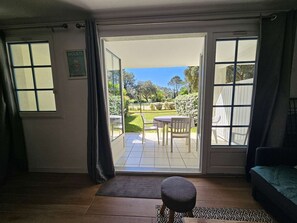 Ein Zimmer mit einer Schiebetür zu einer Terrasse im Freien, mit Tisch und Stühlen.