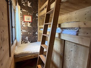 Kerrossänky, jossa on tikkaat, ikkuna ja seinä, jossa on lehmännahkakuvio.