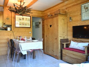 Ein Holzinterieur mit einem für vier Personen gedeckten Esstisch, einem an der Wand montierten Fernseher und einer herzförmigen Aussparung in der Holzwandverkleidung.