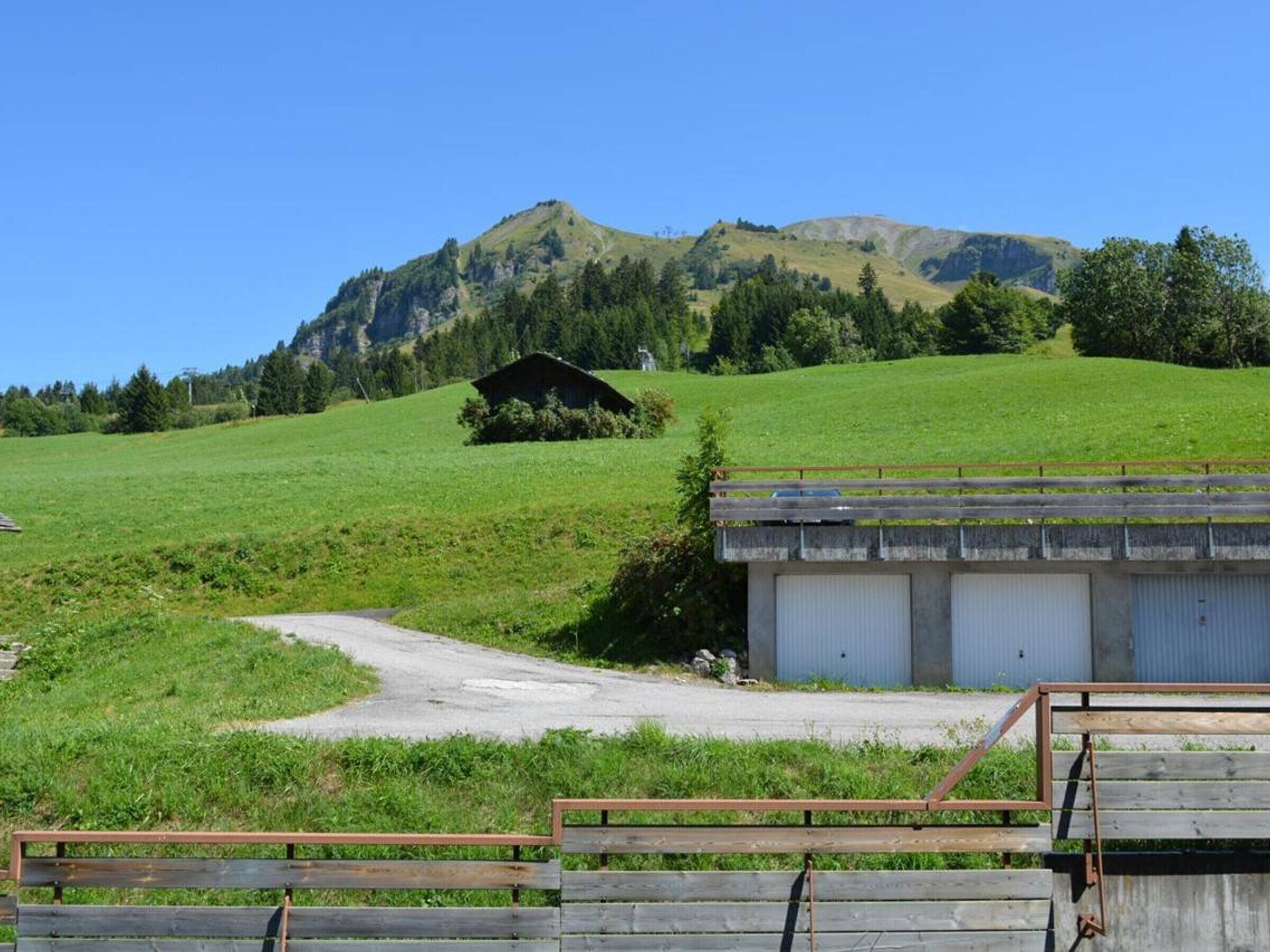 Ländliche Landschaft mit einem Bauernhaus, einer unbefestigten Straße und einem grasbewachsenen Hügel.