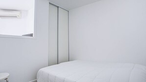 A bedroom with a bed, a window, an air conditioning unit, and a sliding door. - Modern apartment, AC and parking - 3 guests (Canet-en-Roussillon)