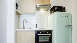 A compact kitchen with a sink, a microwave, a refrigerator, and a built-in oven. - Modern apartment, AC and parking - 3 guests (Canet-en-Roussillon)