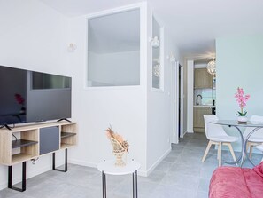 Ein modernes Wohnzimmer mit einem Flachbildfernseher, einem kleinen runden Tisch und einem pinkfarbenen Sofa.