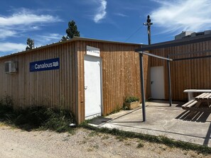 A wooden building with a sign reading 'LesCanalous' and a door labeled 'BUREAU D'ACCUEIL'.