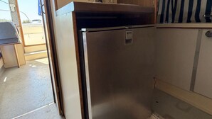 Una cocina compacta con un refrigerador de acero inoxidable, un gabinete de madera y una pequeña encimera.