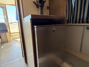 Une cuisine compacte dotĂ©e dâun rĂ©frigĂ©rateur en acier inoxydable, dâun meuble en bois et dâun petit plan de travail.