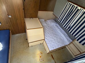 Une petite chambre comprenant un lit, une petite commode et une armoire.