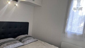 Ein Schlafzimmer mit einem Bett, zwei Nachttischlampen, einem Fenster mit Blick und einem Thermostat.