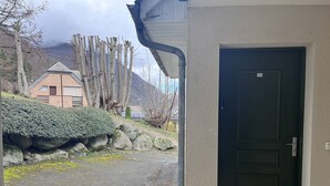 Ein Gebäude mit einer dunklen Tür, einer Steinmauer und einem kleinen Busch.