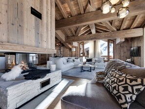 A spacious living area with a fireplace, wooden beams, and a cozy sofa. - Apartment mountain view - 8 guests (Val-d'Isère)