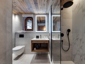 A modern bathroom with a wooden ceiling, a glass shower enclosure, a toilet, a sink with a wooden vanity, and a window with a view of snow. - Apartment mountain view - 8 guests (Val-d'Isère)