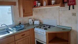 Een kleine keuken met een gasfornuis, een broodrooster en een spoelbak.
