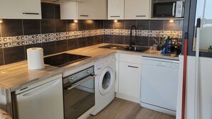 A compact kitchen with a built-in washing machine, a microwave, and a sink. - Renovated apartment, parking, AC, sea view - 4 guests (Canet-Plage)