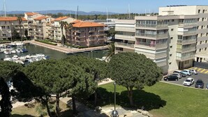 A marina with boats, a parking area, and multi-story residential buildings with balconies. - Renovated apartment, parking, AC, sea view - 4 guests (Canet-Plage)