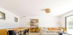 Ein modernes Wohnzimmer mit Essbereich, einer Sofagarnitur, einem Bücherregal und einer Deckenleuchte.