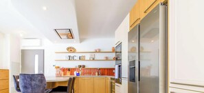 Eine moderne Küche mit Holzausstattung, einem Edelstahlkühlschrank und einem Essbereich mit Tisch und Stühlen.