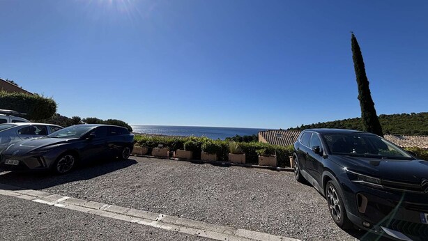 A parking area with two cars, a clear sky, and a view of the sea. - Studio cabin sea view - 3 guests (Cavalaire-sur-Mer)