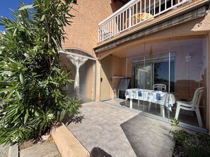 Eine Terrasse mit Tisch und Stühlen, eine Glastür und ein Balkon mit Geländer.