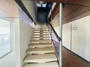Eine Treppe mit Glastrennwand, die zu einer Zwischenebene mit einer Tür und einem Fenster führt.