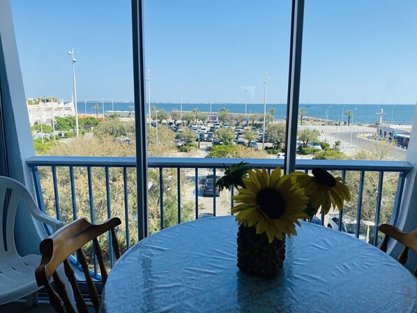 Ein Balkon mit Tisch, Stühlen und einer Vase mit Sonnenblumen.