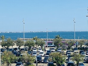 Ein Parkplatz mit Autos, einer Steinmauer und Blick aufs Meer.