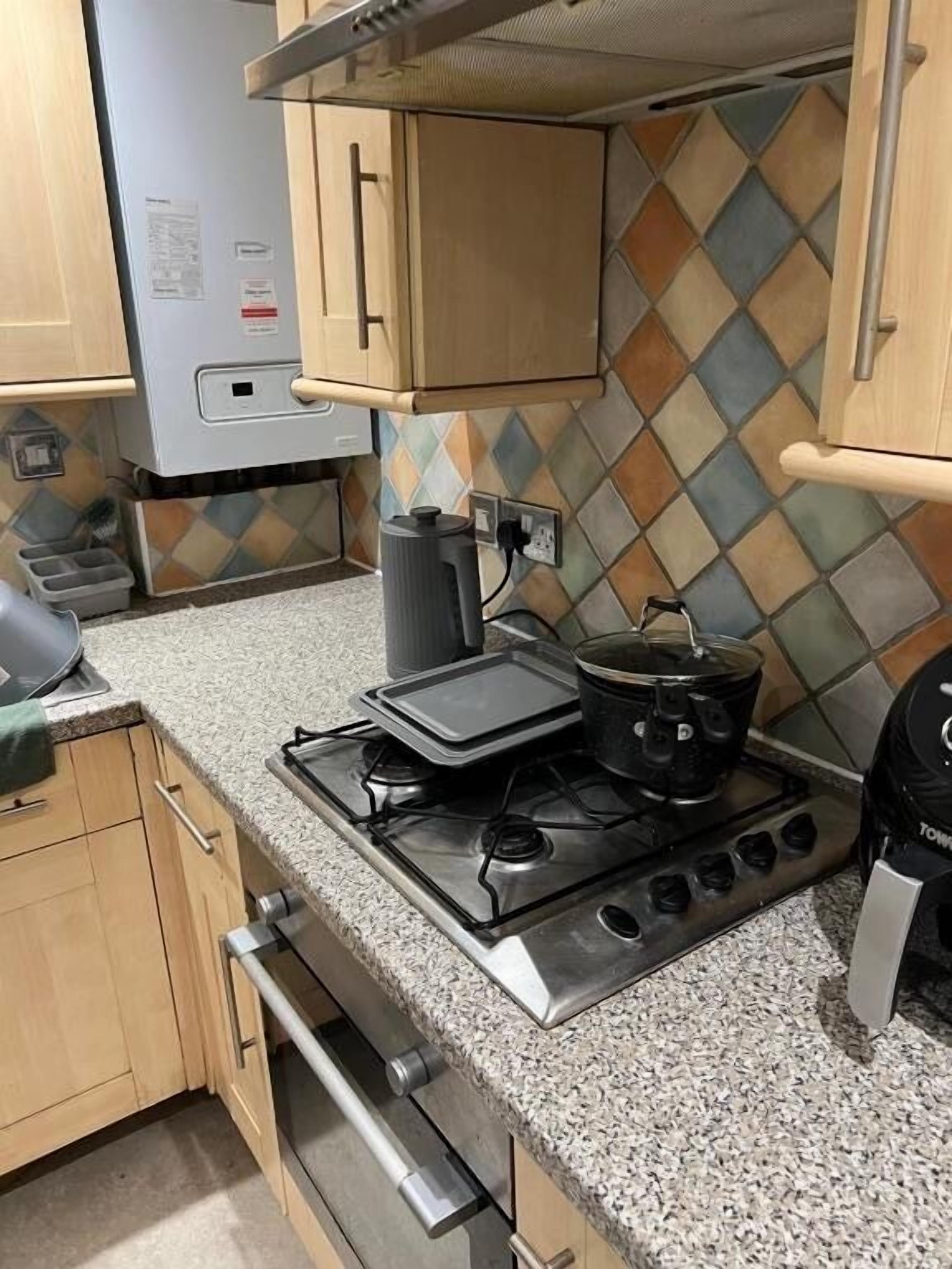 Una cocina con estufa a gas, hervidor y microondas.