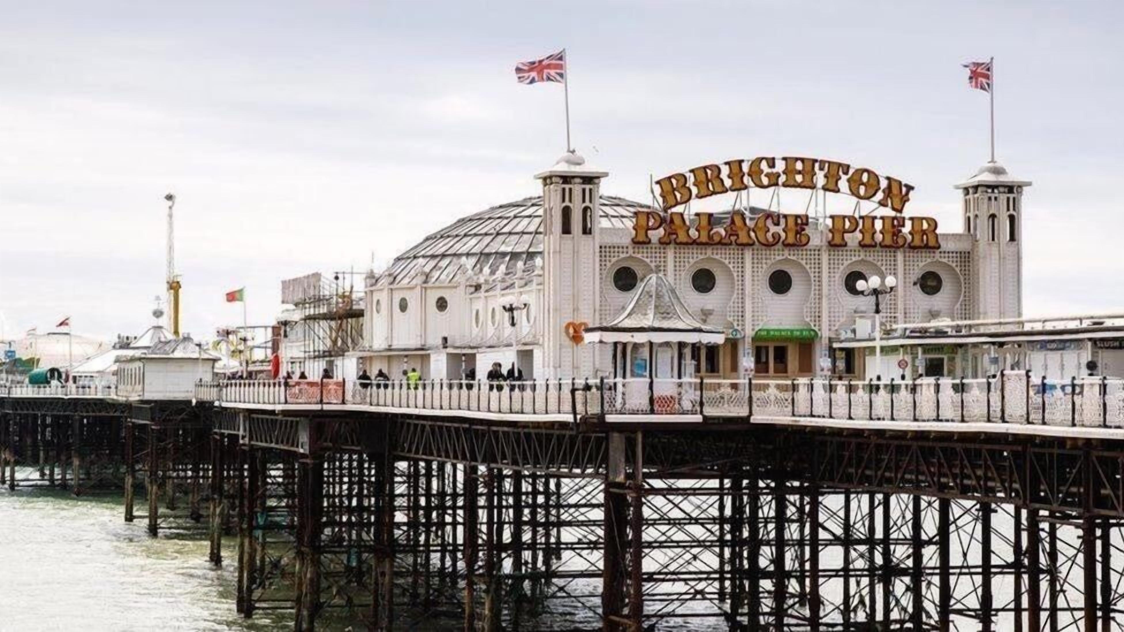 Muelle Brighton Palace con un cartel llamativo, un espigón que se adentra en el agua y una bandera británica.