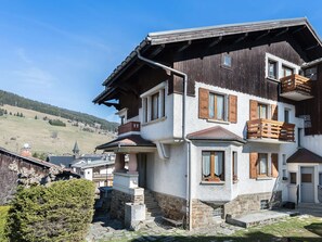Ein mehrgeschossiges Gebäude mit rustikalem Steinunterbau und Holzfassade, inklusive Balkon.