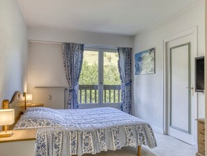 A bedroom with a bed, a radiator, a window with curtains, a door, and a painting on the wall. - Spacious apartment, Mont-Blanc view - 6 guests (Megève)