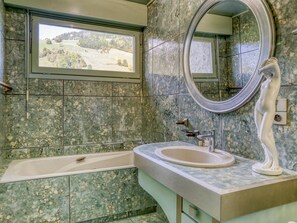 A bathroom with a bathtub, a sink, a mirror, and a window with a view of a landscape. - Spacious apartment, Mont-Blanc view - 6 guests (Megève)