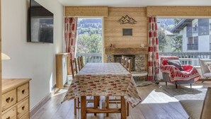 Een eetruimte met een tafel gedekt voor vier personen, een open haard, houten wanden en uitzicht op een berglandschap.
